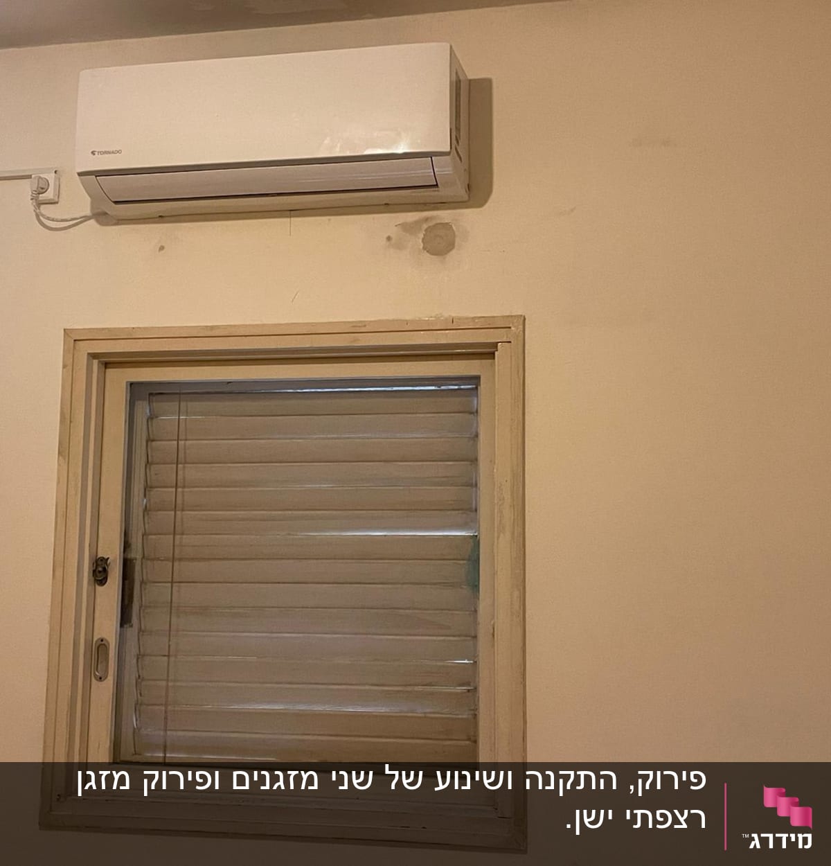 מזגן מותקן על קיר מעל חלון קטן